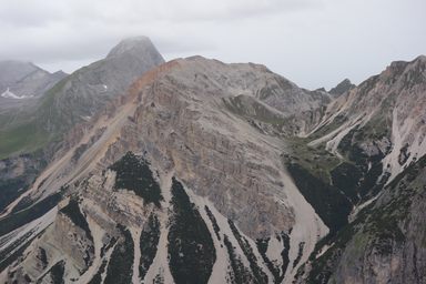 Al bordo destro Furcia dai Fers de fora 2534 (si vede il croce sulla cima). Nel centro Monte Sella de Fanes (Antoniusspitze o Piz de Sant’Antone) 2665. Sullo sfondo Sasso delle Nove - Neunerspitze (Sass de les Nü) 2968